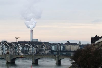 Bridge over river in city against sky