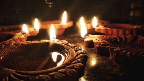 Close-up of lit diyas on table during diwali