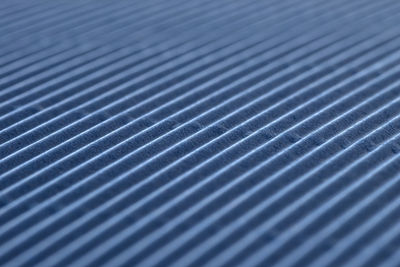 Background made of blue corrugated cardboard with diagonal stripes, shallow depth of field.