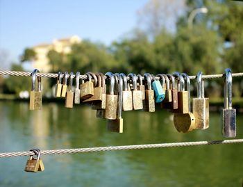 Close-up of padlocks hanging from railing against river