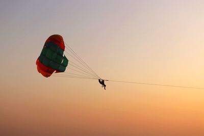 Low angle view of paragliding against sky during sunset