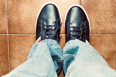 Low section of man standing on tiled floor