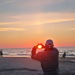 Man standing on beach against sky during sunset