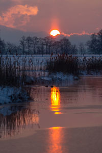 Scenic view of frozen lake against orange sky