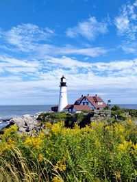 Lighthouse by sea against sky