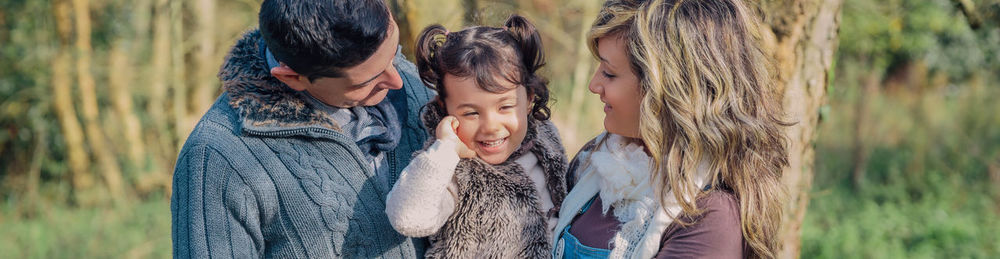 Panoramic view of parents with cute daughter standing in forest