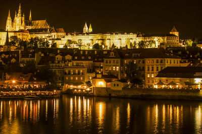 Illuminated cityscape by vltava river at night