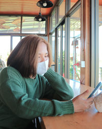 Midsection of woman using phone while sitting on table