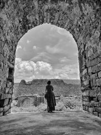 Rear view of woman standing against the wall