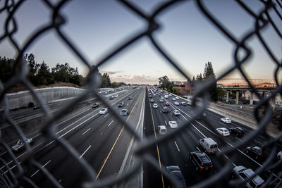 Traffic on road seen through chainlink fence