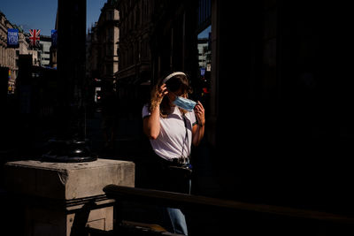 Woman photographing with mobile phone standing in city