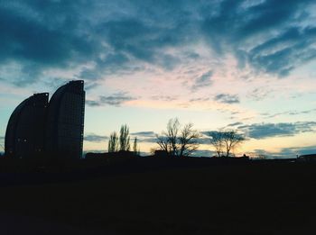 Silhouette of trees against cloudy sky at sunset