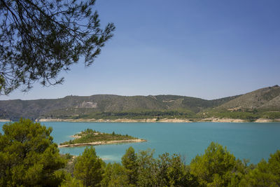 Scenic view of lake and mountains against clear blue sky