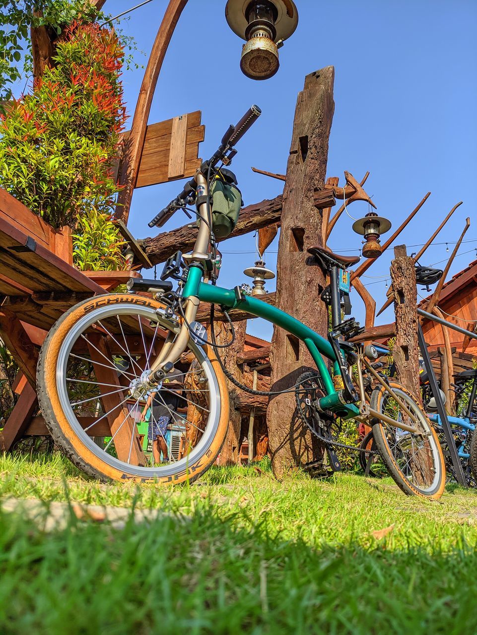 transportation, bicycle, plant, grass, nature, mode of transportation, vehicle, sky, no people, day, sports equipment, land vehicle, blue, outdoors, architecture, clear sky, mountain bike, wheel, cycle sport, travel, tree, green, sunlight, basket, field, sports