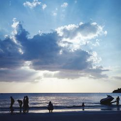 Silhouette people on beach against sky during sunset