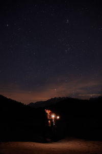 Couple with sparklers under the winter night sky and milky way.