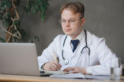 Portrait of doctor using laptop while sitting on table