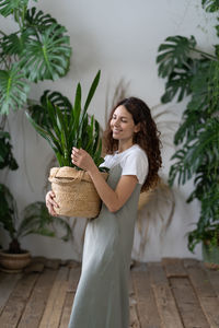 Smiling female gardener taking care about snake plant while working in home garden