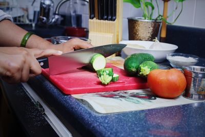 Close-up side view of hands cutting vegetables