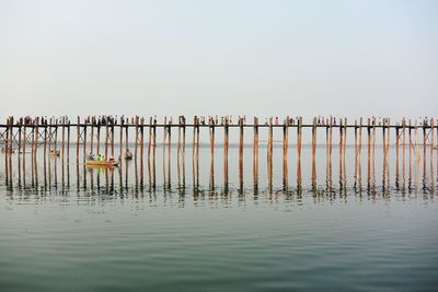 People on pier over lake against cloudy sky