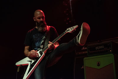 Man playing guitar against black background