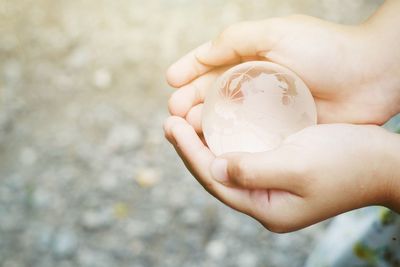 Close-up of hands holding globe outdoors