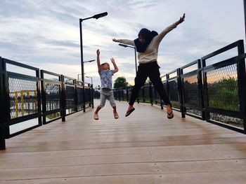 Men jumping on railing against sky