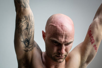 Shirtless bald man exercising against gray background