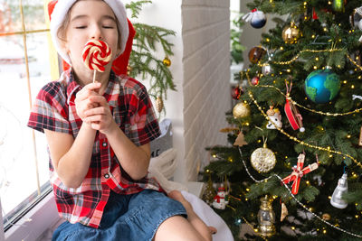 Young woman holding christmas tree at home