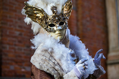 Portrait of man wearing venetian mask against brick wall