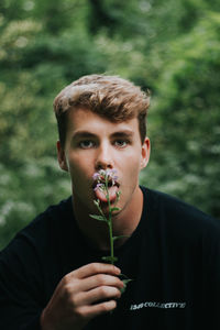 Portrait of young man holding flowering plant