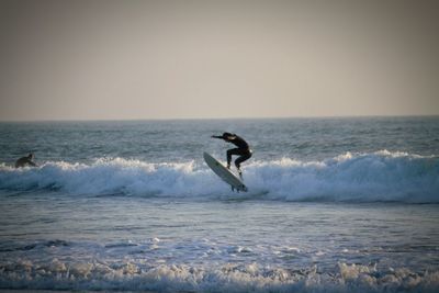 Side view of a man surfing in sea against clear sky