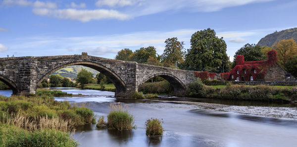 Arch bridge over river against sky