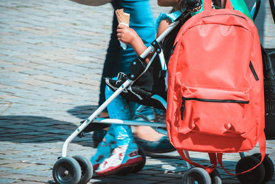 Low section of girl sitting on baby carriage