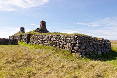 Stone wall on field against sky