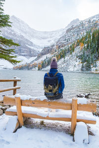 Rear view of man sitting on snowcapped mountain