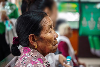 Side view of wrinkled senior woman sitting at home