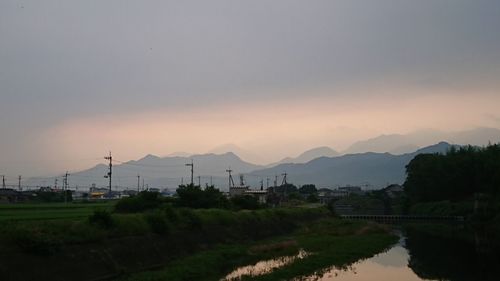 Scenic view of agricultural field against sky at sunset