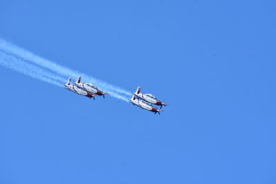 Low angle view of airplane flying against clear blue sky