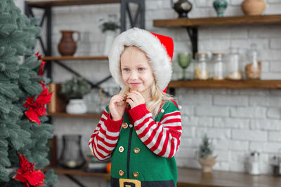 Girl in santa claus hat smiling and eating christmas cookie