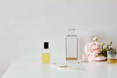 Still life with perfumes, whiskey, necklace, roses