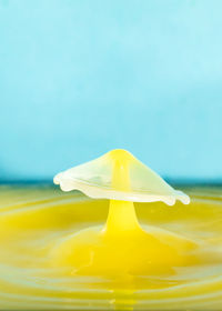 Close-up of yellow glass over sea against blue background