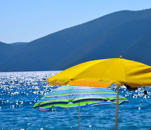 Yellow umbrella on beach against clear blue sky
