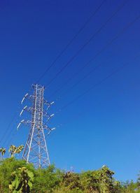 Low angle view of electricity pylon against clear blue sky
