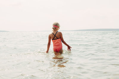 Full length of woman standing in sea against sky