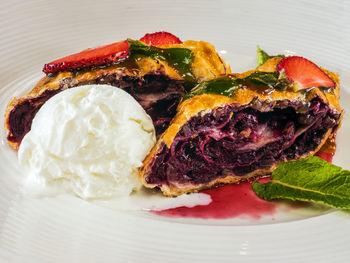 Close-up of cherry strudel served with ice cream in plate on table