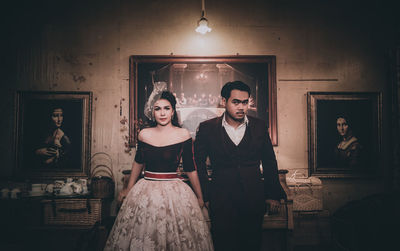 Portrait of couple standing against picture frames
