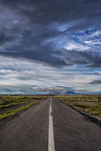 Empty road against cloudy sky