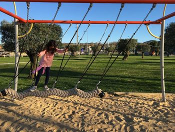 Girl swinging on rope swing at playground