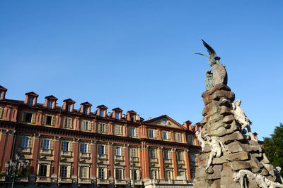 Low angle view of statue against building against clear sky